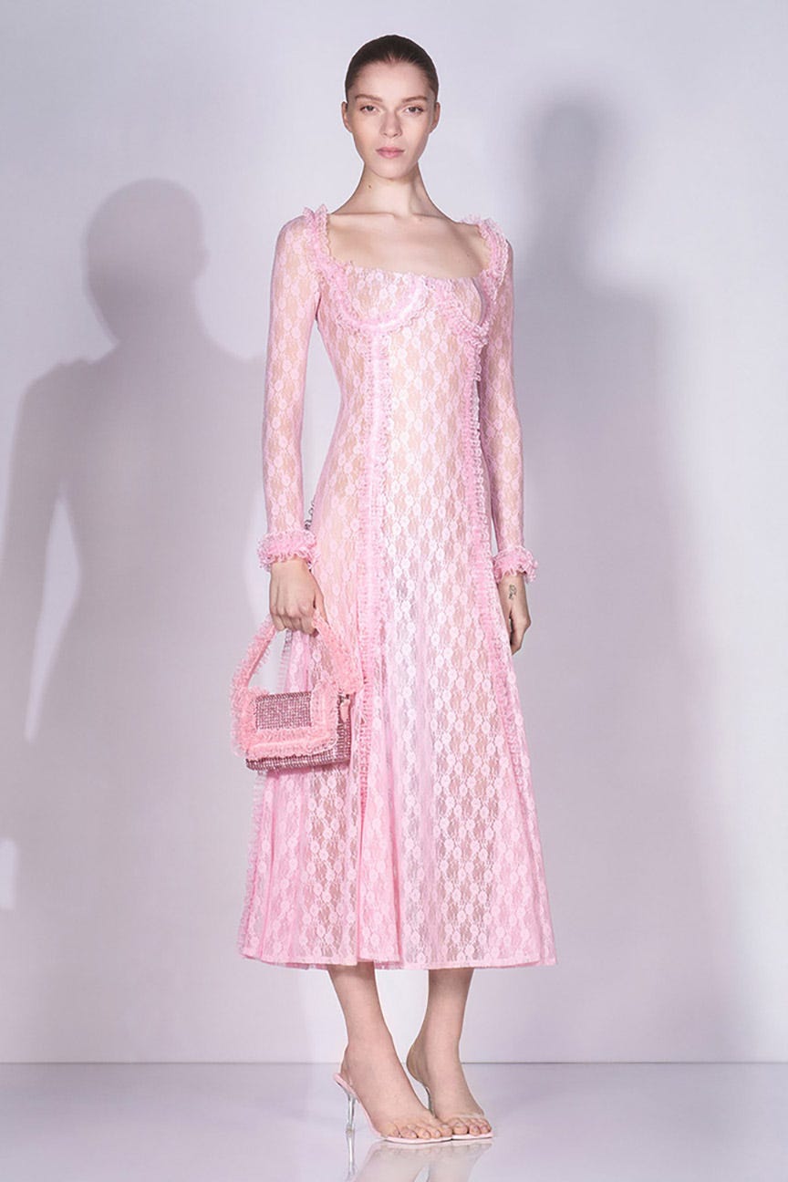 model wearing a pink lace dress and holding a matching handbag