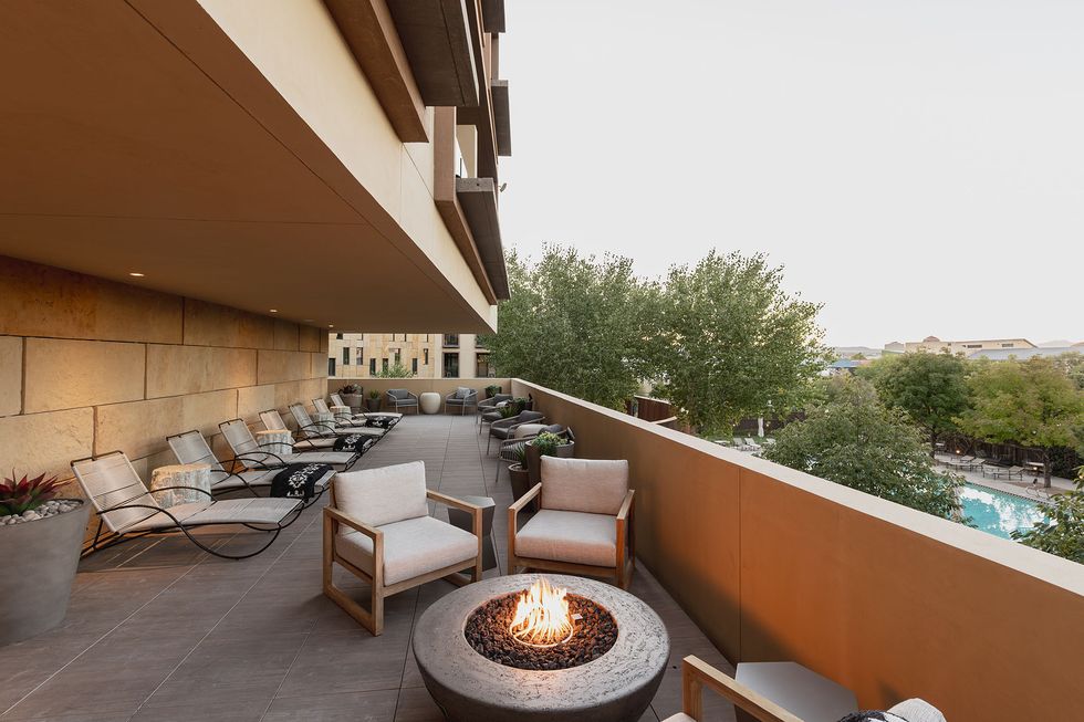 a patio with chairs and a fire pit with a fire in it