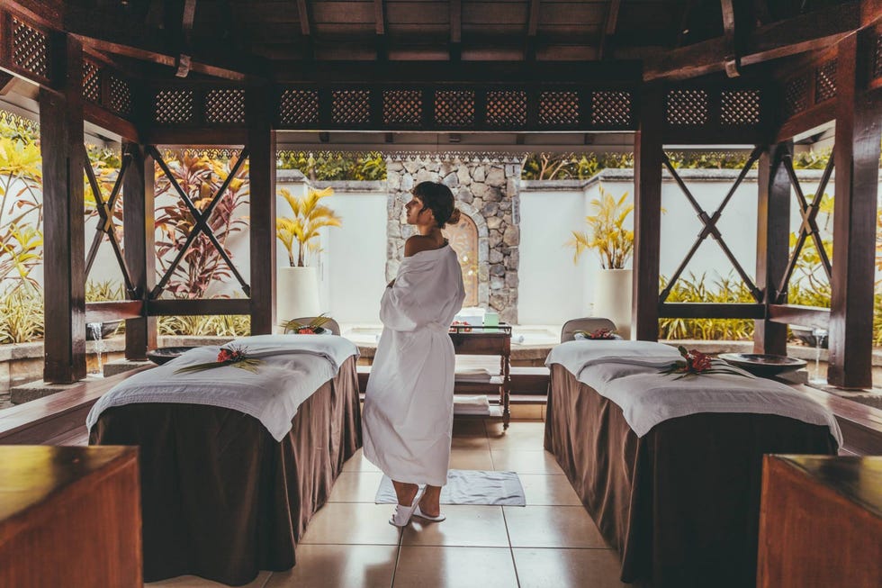 a person in a white dress standing in a room with a table and chairs