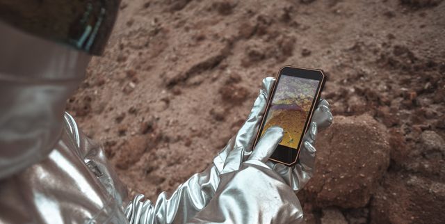 Spaceman examining new planet, using smartphone