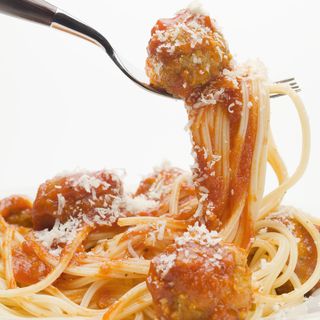 Spaghetti and one meatball in tomato sauce on a fork