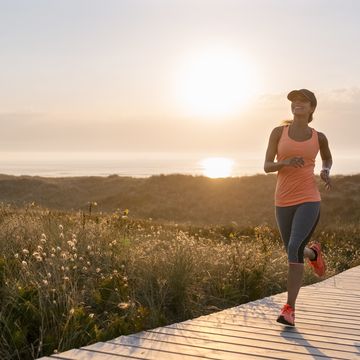 spain, aviles, young athlete woman running along a coastal path at sunset