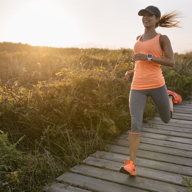 spain, aviles, young athlete woman running along a coastal path at sunset