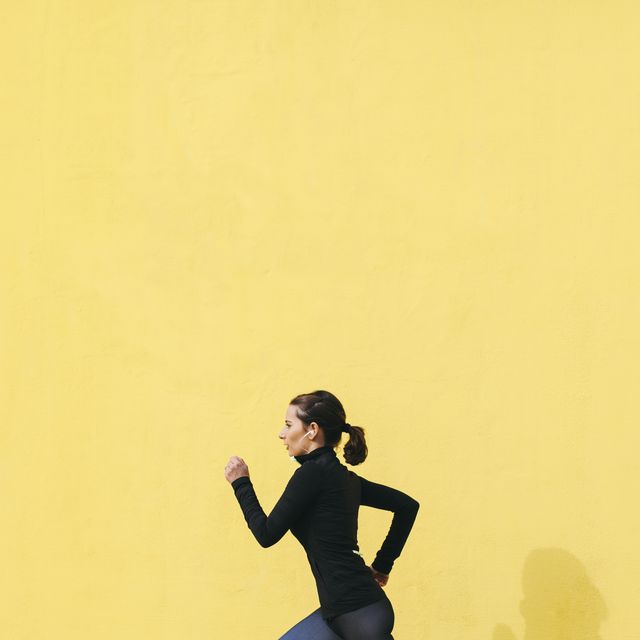jogging woman in front of yellow wall