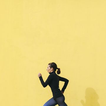 jogging woman in front of yellow wall