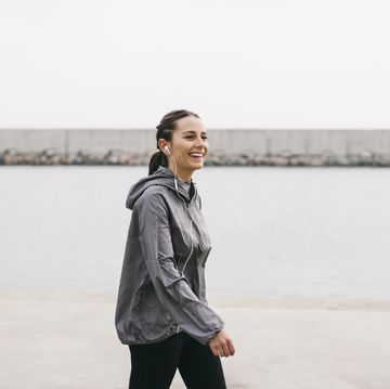 spain, barcelona, jogging woman with headphones at harbour