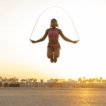 spain, barcelona, young black woman skipping rope at sunrise