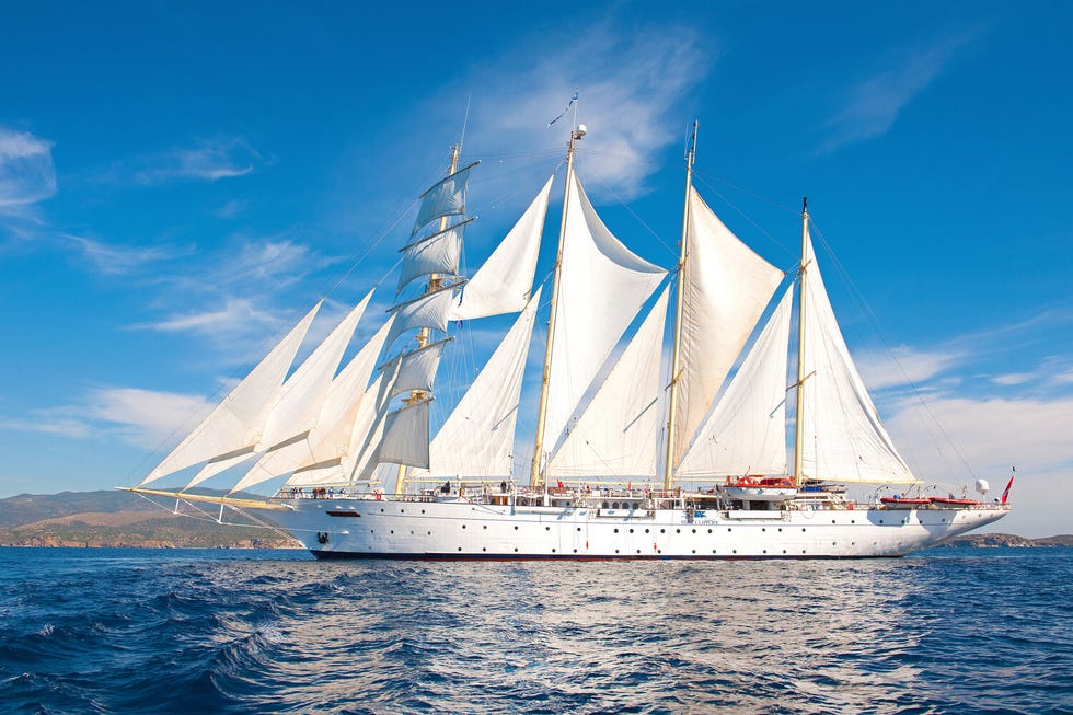 sailing ship with multiple white sails on the ocean under a blue sky