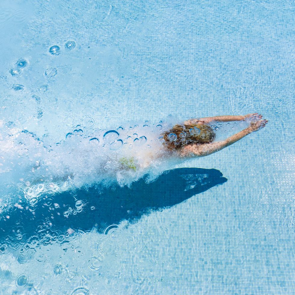 spain, woman diving in swimming pool