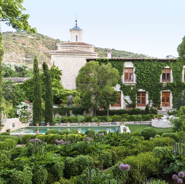 17th century palace in tendilla, spain design by alvaro sampedro beyond a lush oasis dotted with italian cypress and linden trees, boston ivy climbs the spanish palaces facade