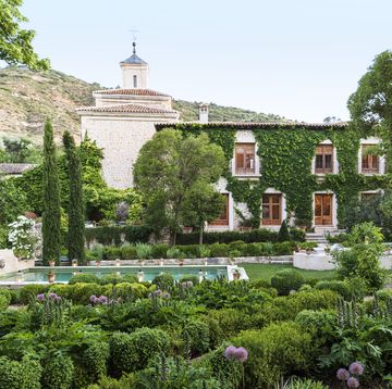 17th century palace in tendilla, spain design by Álvaro sampedro beyond a lush oasis dotted with italian cypress and linden trees, boston ivy climbs the spanish palace’s facade