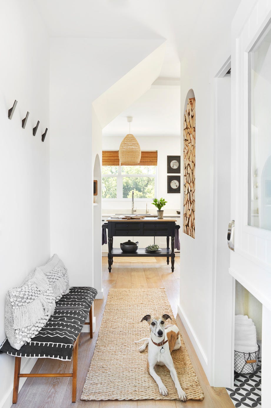 dog lying on a jute rug in the hallway of a modern farmhouse entry seen through a dutch door with kitchen and bathroom in the background