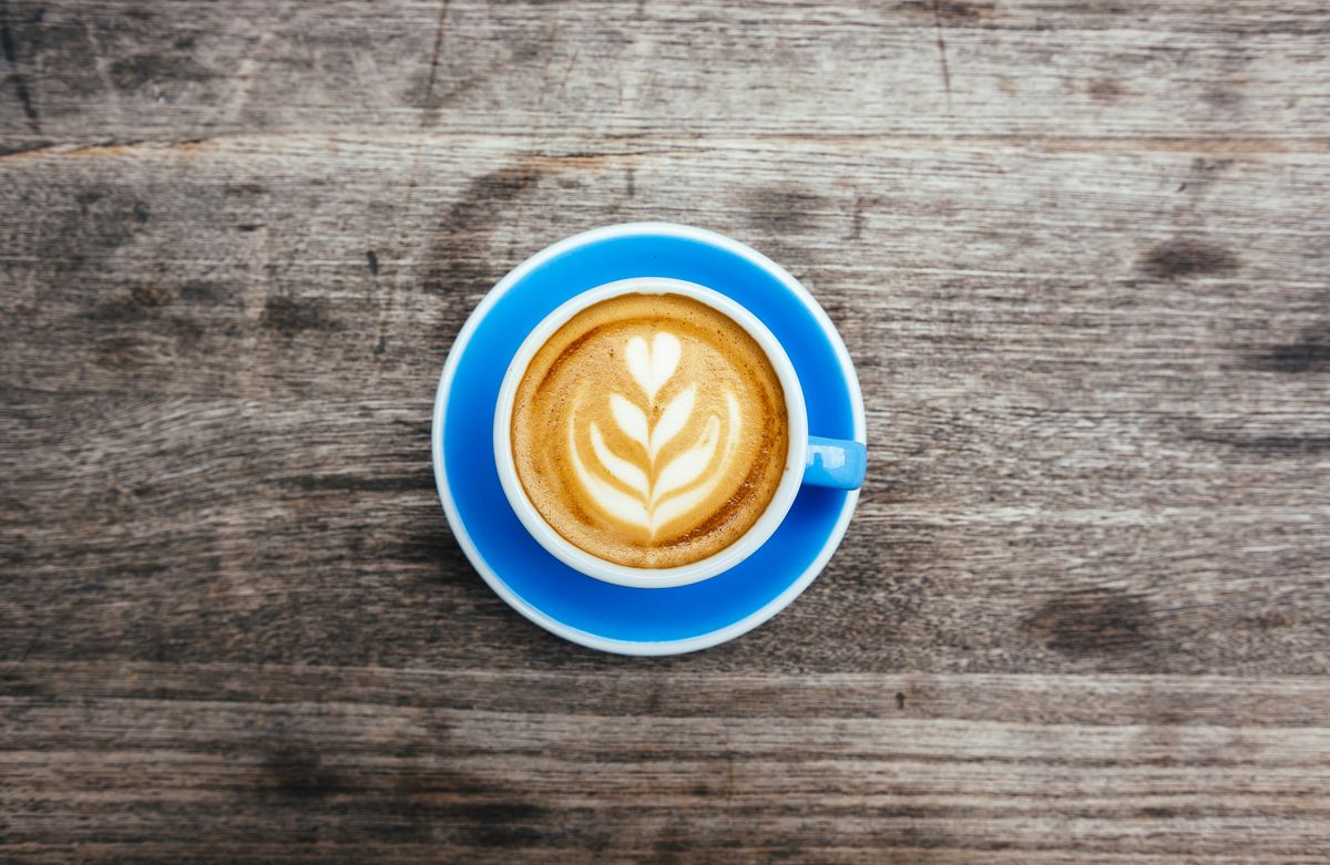 foamy coffee latte with design in blue mug