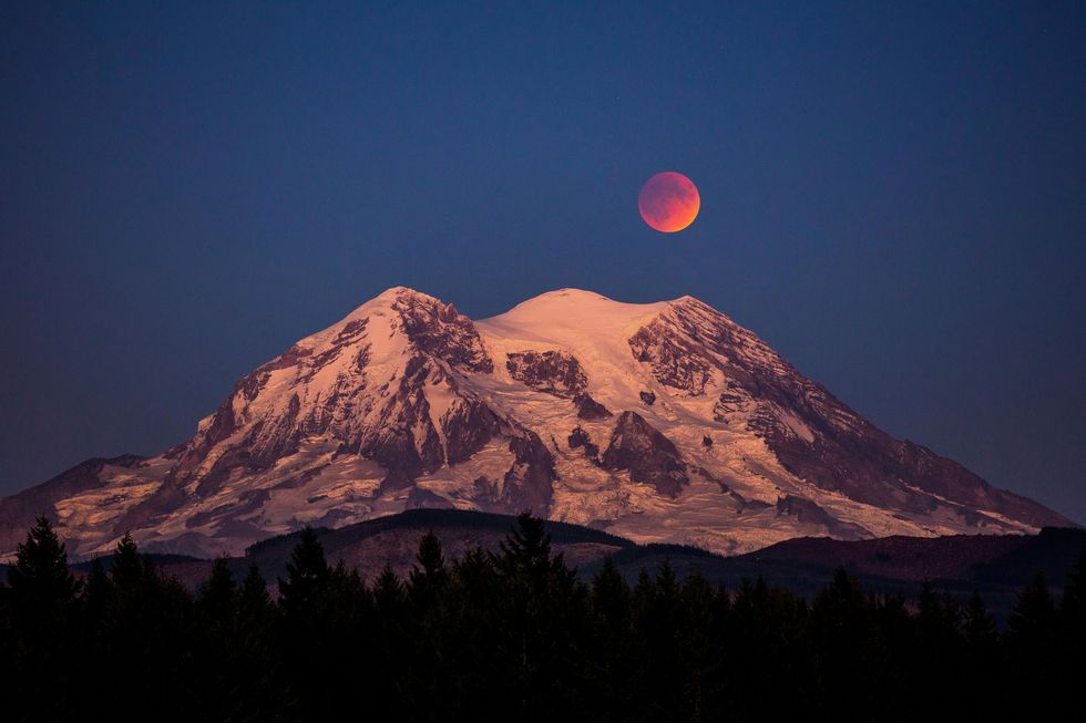 Een totale maansverduistering  die soms wordt aangeduid met de onheilspellende term bloedmaan  is te zien boven Mount Rainier in de staat Washington