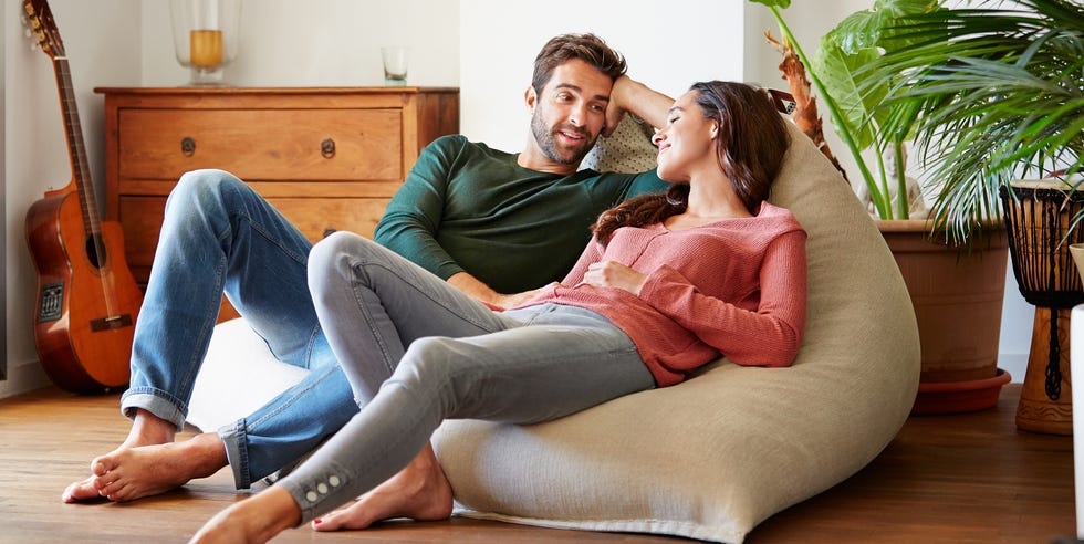 Pasar el día relajándonos juntos foto de una joven pareja sonriente hablando juntos mientras se relajan en un sofá de puf en casa