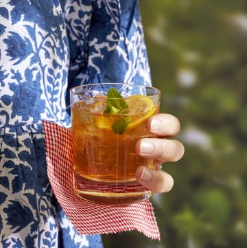 a person holding a glass of spicy ginger beer and bourbon cooler