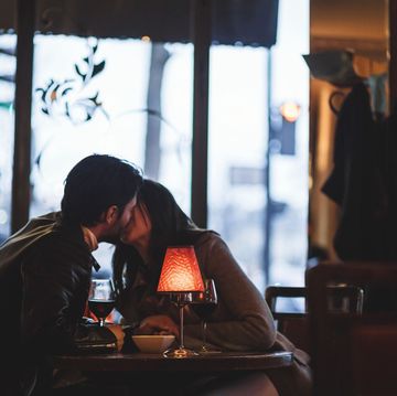 vrouw en man kussen aan tafel in restaurant