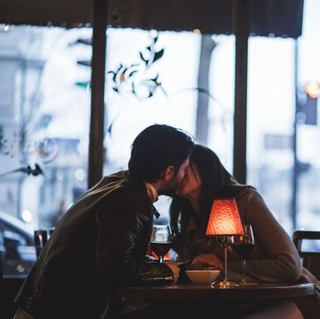 vrouw en man kussen aan tafel in restaurant