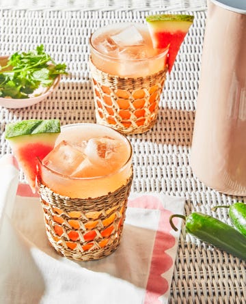 a couple of glasses with spicy watermelon paloma and fruit in them