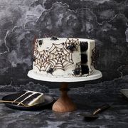 chocolate cake with white frosting, decorated with chocolate spider webs and spiders