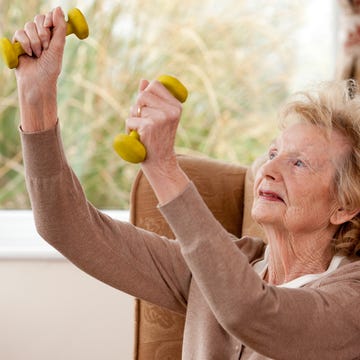 oude vrouw houdt gewichten vast om spieren op te bouwen