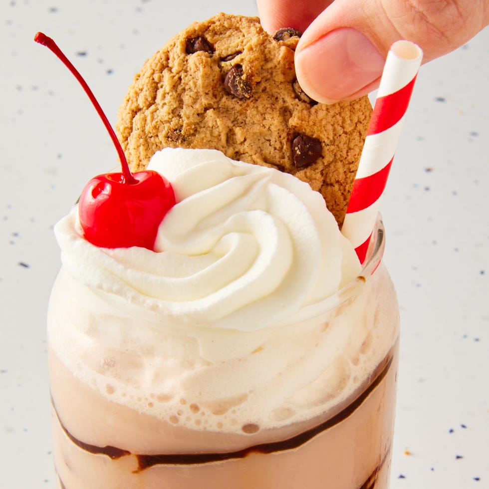 chocolate egg cream topped with whipped cream, a cherry, and a chips ahoy cookie