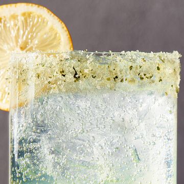 spiked sparkling basil lemonade in a glass garnished with a basil sugar rim and a lemon wheel