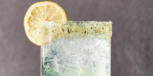 spiked sparkling basil lemonade in a glass garnished with a basil sugar rim and a lemon wheel