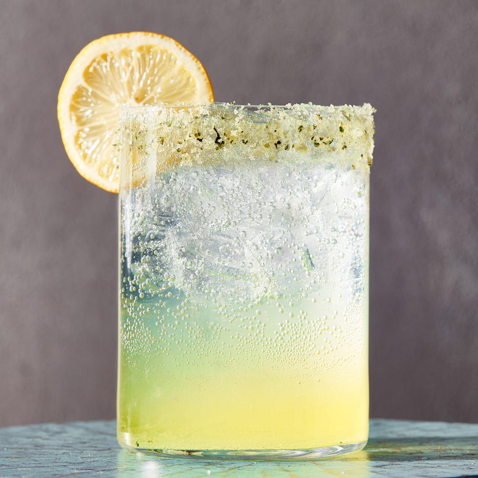 spiked sparkling basil lemonade in a glass garnished with a basil sugar rim and a lemon wheel
