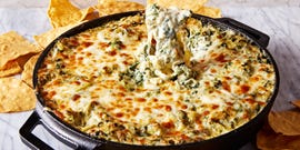 spinach artichoke dip in a cast iron skillet served with tortilla chips