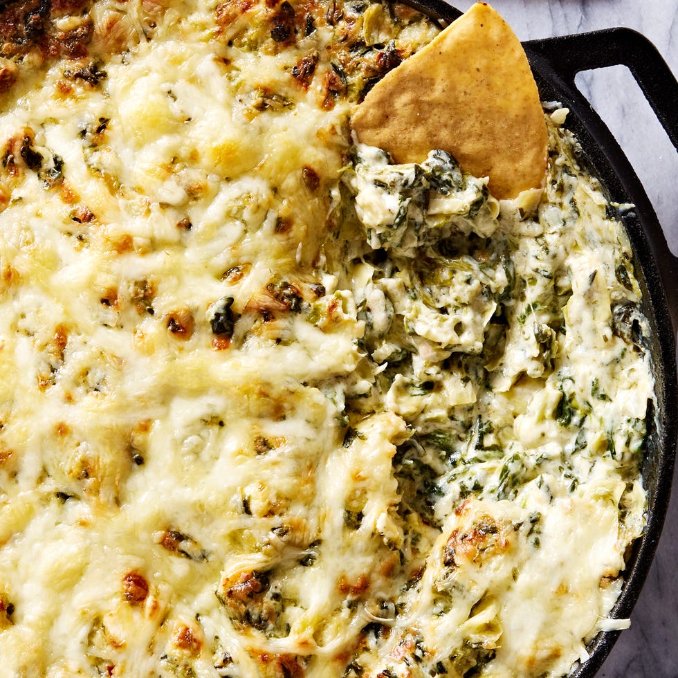 spinach artichoke dip in a cast iron skillet served with tortilla chips