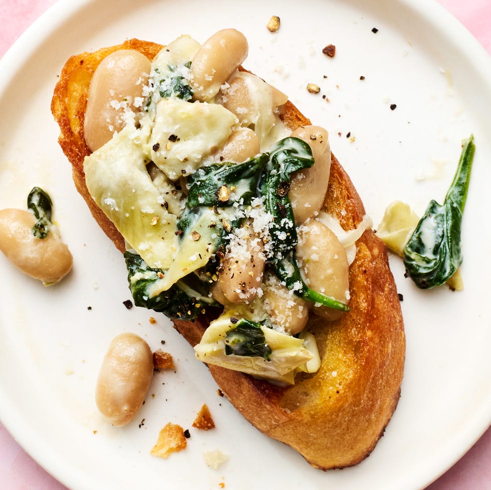 white beans in a skillet with spinach, artichokes, and cheese