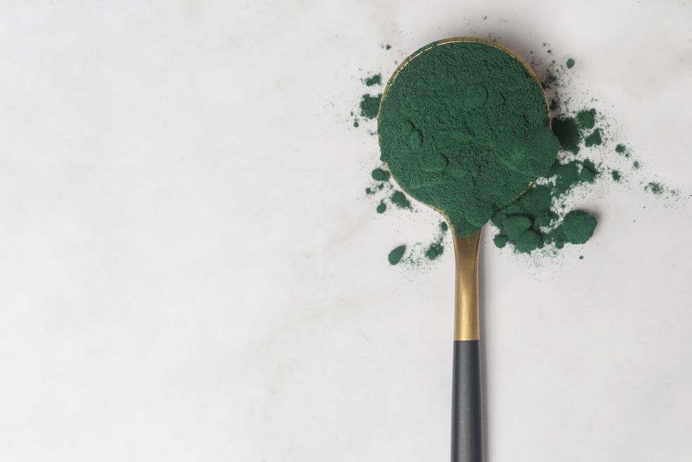 green powder in the spoon, spirulina, alage, alfalfa, chlorophyll or matcha concept of nutritional supplement, dieting, detox, preventive healthcare and healthy lifestyle