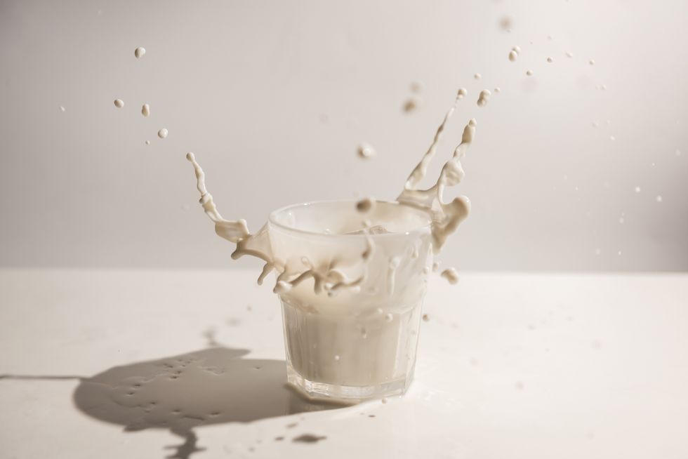 splash of milk from the glass on a white table, dairy concept