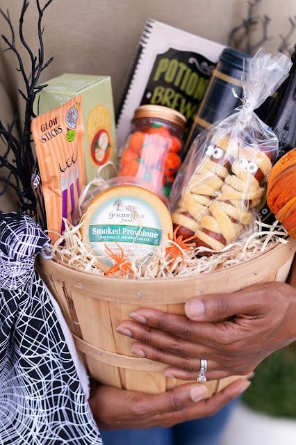 a spooky basket with a gourmet theme featuring food items like sausages that look like mummies made from sausages wrapped in croissant dough and candy eyes