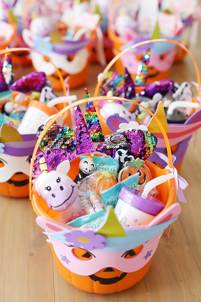 spooky basket idea from see vanessa craft the bucket is a jack o lantern face wearing a mask, and it's filled with treats