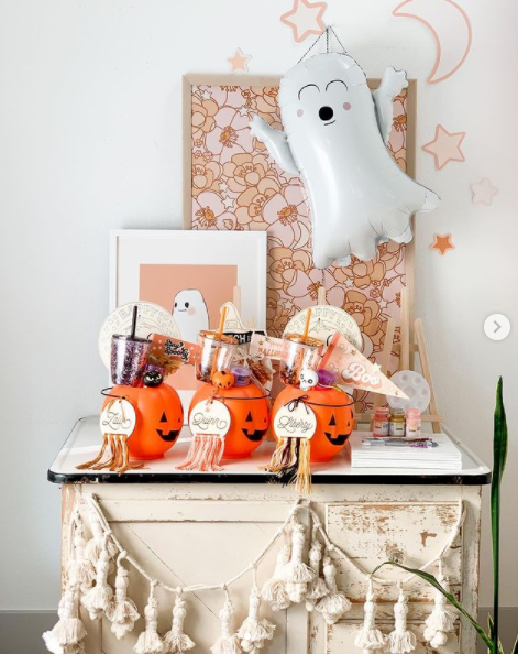 three pumpkin shaped spooky baskets lined up on a table with ghost decorations on it