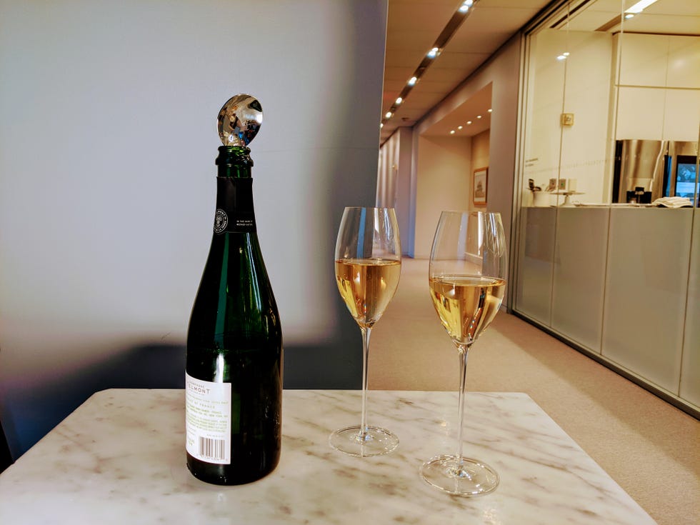 spoon handle in bottle of champagne alongside two glasses of champagne