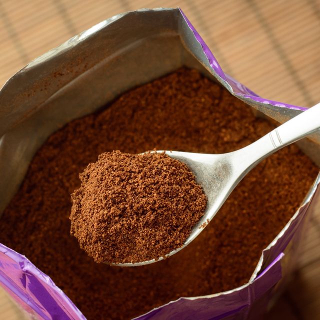 spoon with some ground coffee against a big pack of coffee