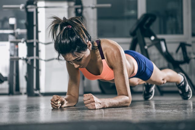 Sport. Muscular woman on a plank position.