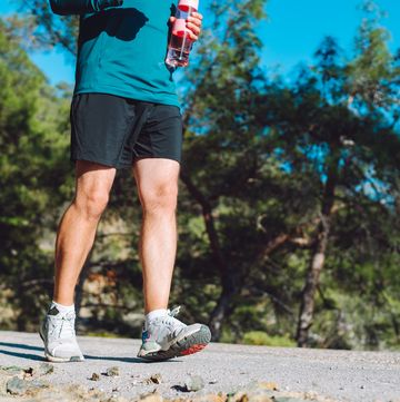 sport shoes unrecognisable man run along a road in mountain area
