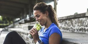 sportive young woman sitting on grandstand with cell phone and drinking mug
