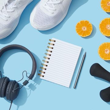 sports equipment and accessories, shoes, dumbbells, notebook and oranges on blue background