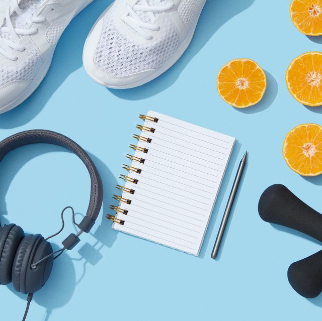 sports equipment and accessories, shoes, dumbbells, notebook and oranges on blue background