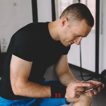 Sportsman in the gym texting on smartphone