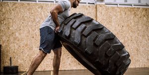 Sportsman Pushing Tire On Cross Training In Gym