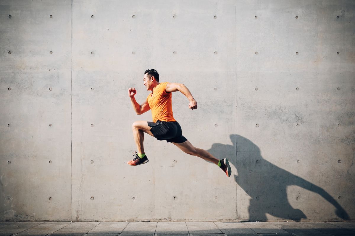 sporty asian mid man running and jumping next to wall