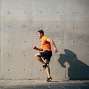 sporty asian mid man running and jumping against shutter health and fitness concept