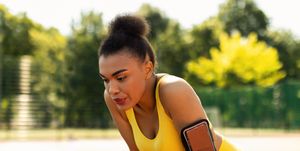 nasal breathing while Public running sporty black woman in yellow sportswear resting after run