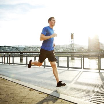 sporty man jogging on promenade against sky